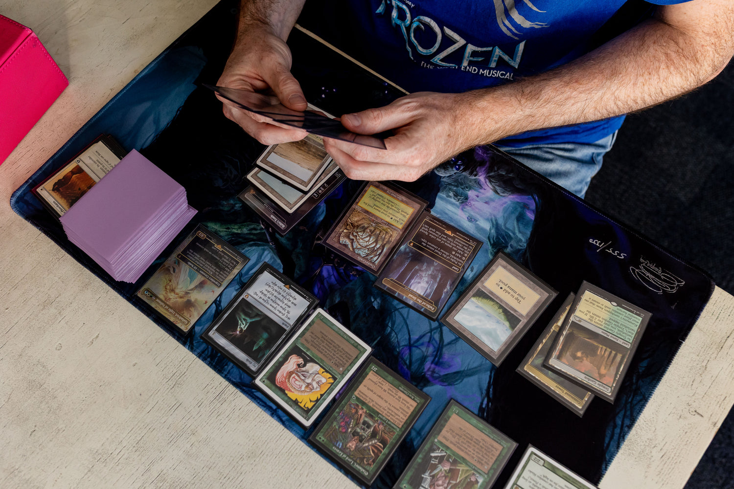Simon organising trading cards on a playmate mat wearing with a 'Frozen' shirt